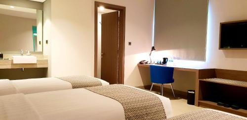 a hotel room with two beds and a desk at BW inn Belitung in Tanjungpandan