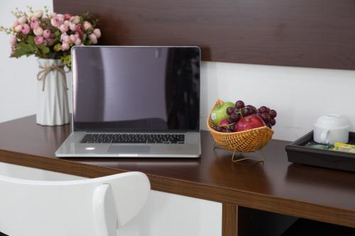 a laptop computer sitting on a desk with a bowl of fruit at Mama Hotel And Apartment - Free Sauna And Gym in Da Nang