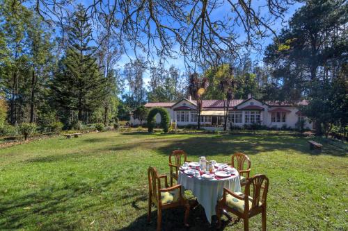 una mesa en el patio de una casa en SaffronStays Milton Abbott Estate - 2BR colonial-era bungalow with garden, golf course views & bonfire nights near Ooty Golf Club, en Ooty