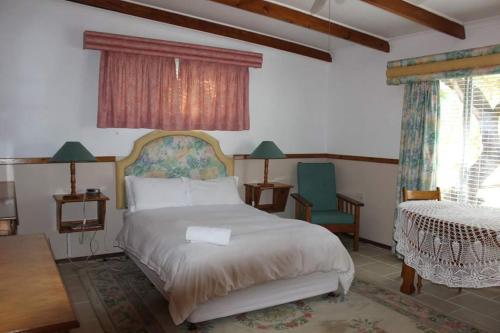 Un dormitorio con una cama y una mesa y sillas. en Lord Fraser Guest House, en Wepener