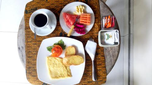 a table with two plates of food and a cup of coffee at Umah Dajane Guest House in Ubud