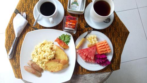 a table with two plates of food and cups of coffee at Umah Dajane Guest House in Ubud