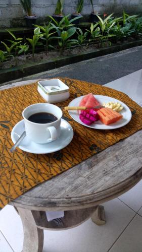 a cup of coffee and a plate of fruit on a table at Umah Dajane Guest House in Ubud