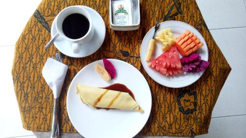 a table with two plates of food and a cup of coffee at Umah Dajane Guest House in Ubud