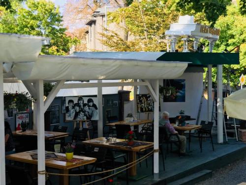 een openluchtrestaurant met tafels en een witte luifel bij Willa Sorrento in Szczecin
