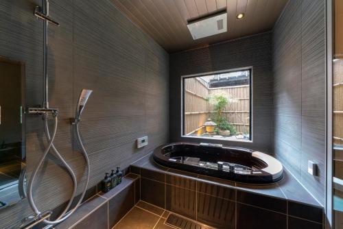 a bathroom with a tub and a shower with a window at Ainotsuji Machiya House in Kanazawa