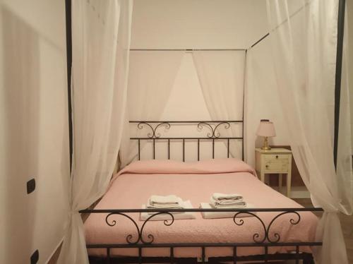 a bedroom with a bed with pink sheets and curtains at Il Portico in Carrosio