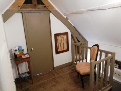a room with a staircase with a chair and a door at La "charcuterie" GREBER in Beauvais