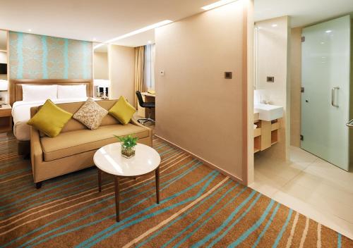 a hotel room with a couch and a sink at Cosmo Hotel Kuala Lumpur in Kuala Lumpur
