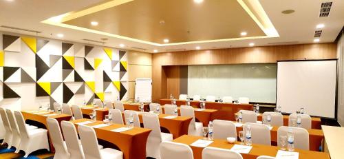 a conference room with tables and chairs and a screen at BW inn Belitung in Tanjungpandan