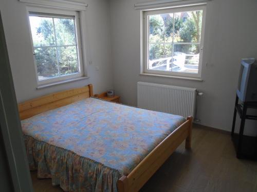 a small bedroom with a bed and two windows at BLANKENBERGE FLAT in Blankenberge