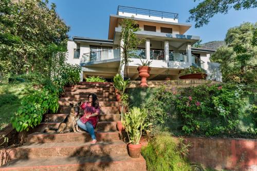 a woman sitting on the stairs of a house at SaffronStays Masaya, Alibaug - pet-friendly villa with alfresco dining in Alibaug