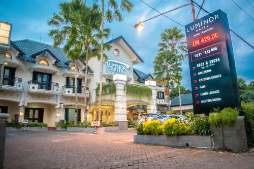ジェンベルにあるLuminor Hotel Jember By WHの建物の前に看板があるホテル