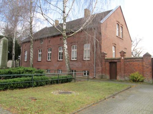 un gran edificio de ladrillo con un árbol delante de él en Herberge im "alten Pfarrhaus" in Schmergow am Havel-Radweg, en Schmergow