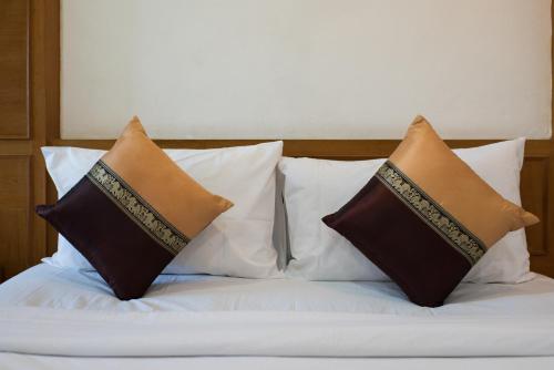 a bed with three pillows on top of it at Magnific Patong in Patong Beach