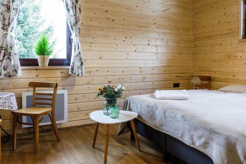 a bedroom with a bed and a table with flowers on it at Villa Bezycer in Gowidlino