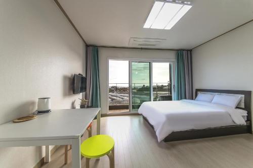 um quarto com uma cama, uma secretária e uma janela em Jeju Soo Pension em Seogwipo