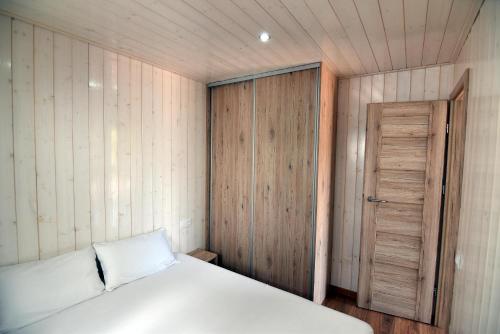 a bedroom with a white bed and a wooden door at Camping La Rueda in Cubelles