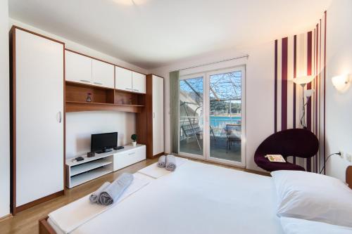 a bedroom with a large white bed and a tv at Apartments Barbir in Ploče