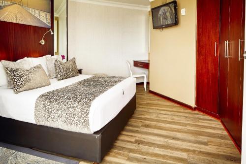 um quarto de hotel com uma cama e uma secretária em First Group The Palace All-Suite em Durban