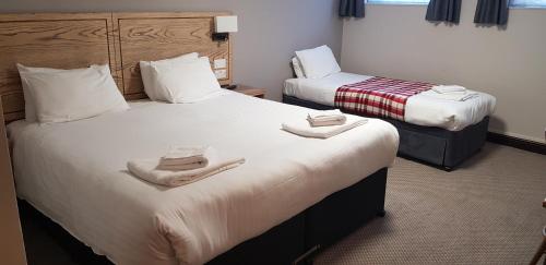 two beds in a hotel room with towels on them at Waterloo Cross, Devon by Marston's Inns in Uffculme