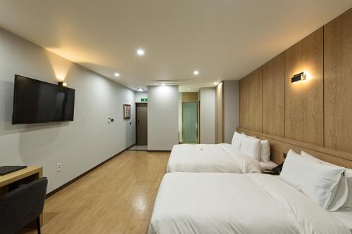 a hotel room with two beds and a flat screen tv at Notte La Mia Hotel in Busan