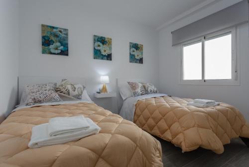 a bedroom with two beds and a window at El TESORO de la Caleta by Cadiz4Rentals in Cádiz
