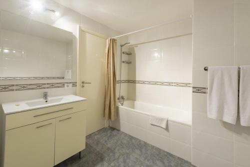a white bathroom with a sink and a bath tub at Castle Harbour Official in Los Cristianos