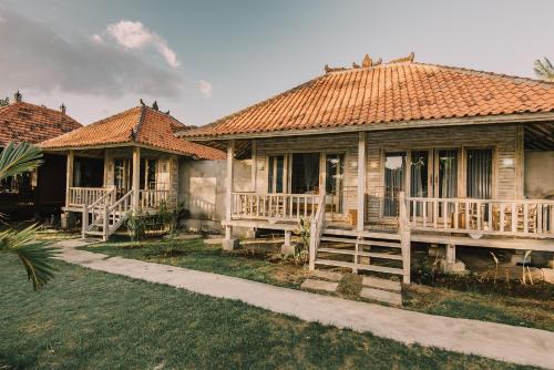 two houses with wooden decks in a yard at The Bridge Huts in Nusa Lembongan