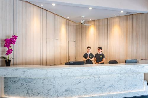 two people are standing behind a reception desk at Coconut Village Resort Phuket - SHA Extra Plus in Patong Beach