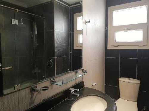 a bathroom with a toilet and a window and a mirror at Luxury Host -219- Dream Land in 6th Of October