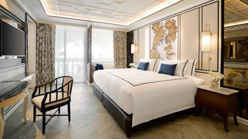 a bedroom with a large white bed and a desk at Mövenpick Myth Hotel Patong Phuket in Patong Beach