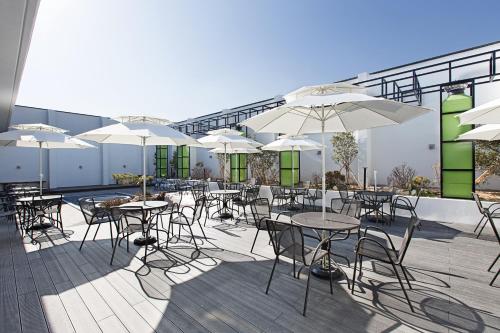 Notte La Mia Hotel في بوسان: مجموعة طاولات وكراسي مع مظلات على الفناء