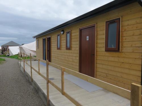 a wooden cabin with a porch and a door at Shannon Estuary Glamping in Effernan