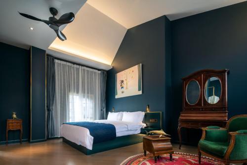 昆明市にあるMoon and Chalice Boutique Hotelの青い壁のベッドルーム1室、ベッド1台、椅子1脚が備わります。
