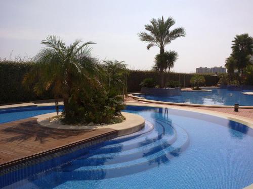 una gran piscina con palmeras en el fondo en CORMORANT SUITE, sea terrace & pools, en La Manga del Mar Menor