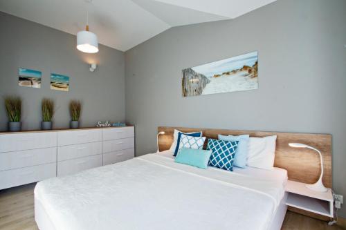 a bedroom with a large white bed with blue pillows at Grand Apartments - Neptun Park Smile&Relax in Gdańsk