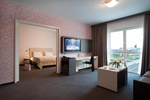 a hotel room with a bed and a desk and a television at Hotel City Maribor in Maribor