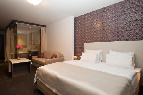 a hotel room with a large bed and a chair at Hotel City Maribor in Maribor