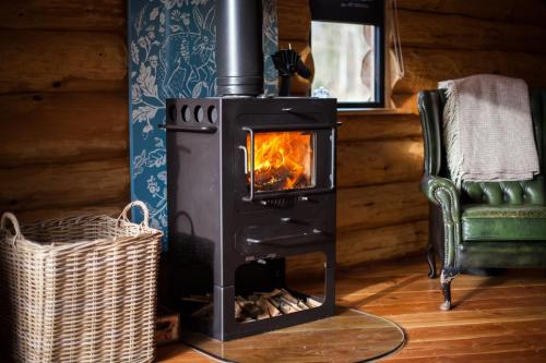 a wood stove in a room with a chair at Coed y Marchog Woodland Retreat in Hereford