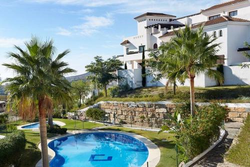 a house with a swimming pool and palm trees at Luxury apartment set in Doña Julia Golf Course in Casares