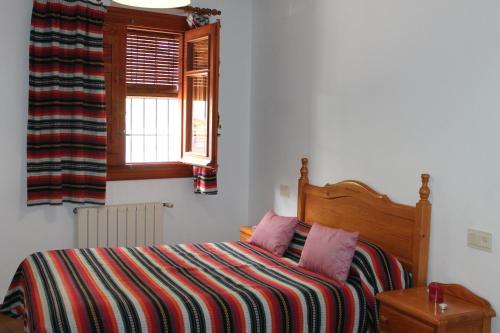 a bedroom with a bed with a striped blanket and a window at Apartamentos Rurales Rosendo: "El Laurel" in Capileira