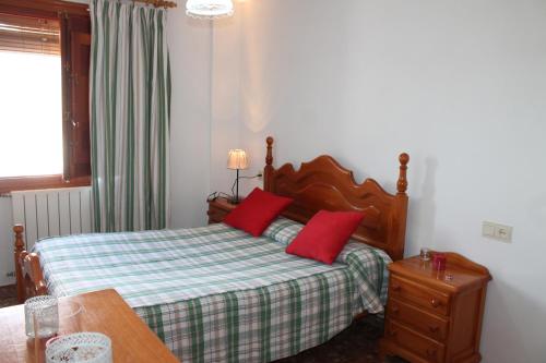 ein Schlafzimmer mit einem Bett mit roten Kissen darauf in der Unterkunft Apartamentos Rurales Rosendo: "Flor de Lys" in Capileira