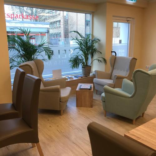 a waiting room with chairs and tables and a large window at Hotel Select Suites & Aparts in Mönchengladbach