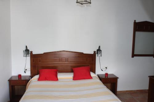 a bedroom with a bed with two red pillows at Apartamentos Rurales Rosendo: "La Pimienta" in Capileira