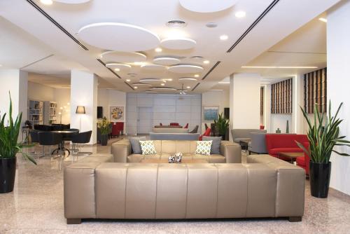 a lobby with a large couch in the middle at Benjamin Business Hotel in Herzelia 