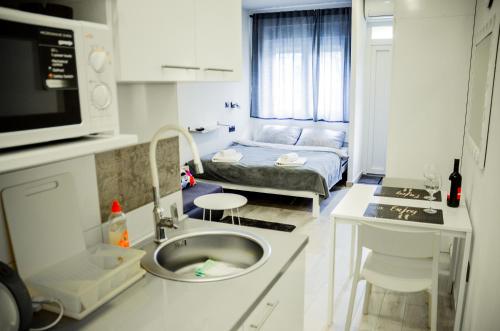 a kitchen with a sink and a room with a bed at Studio Apartment Lukas in Vinkovci
