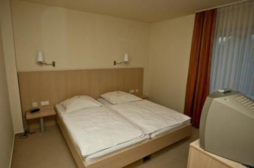 een kleine slaapkamer met een bed en een raam bij Hotel Manu in Paderborn