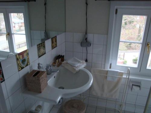 ein weißes Badezimmer mit einem Waschbecken und einem Spiegel in der Unterkunft Elisabeth von Eicken in Ahrenshoop