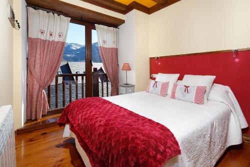 a bedroom with a bed with a red headboard and a window at Apartamento La Santeta de Aran in Vielha